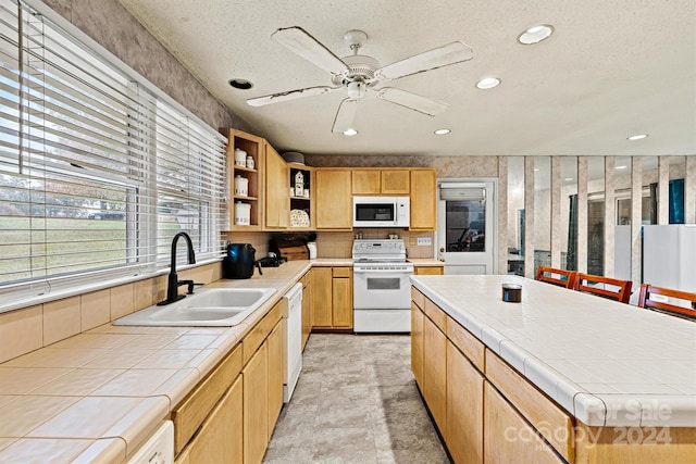 kitchen featuring white appliances, tile countertops, a textured ceiling, and sink