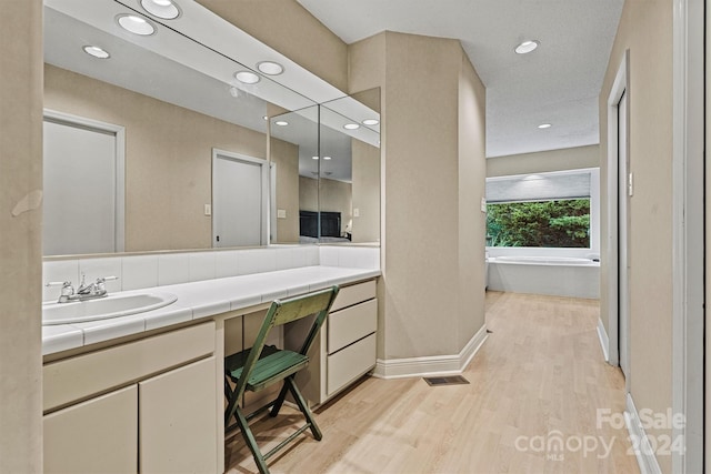 bathroom featuring hardwood / wood-style flooring, vanity, and a tub to relax in