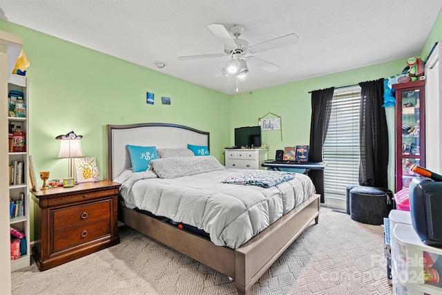 carpeted bedroom featuring ceiling fan and a textured ceiling