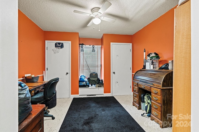 carpeted home office with ceiling fan and a textured ceiling