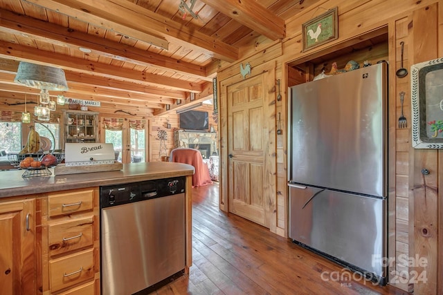 kitchen with beamed ceiling, stainless steel appliances, and wooden walls