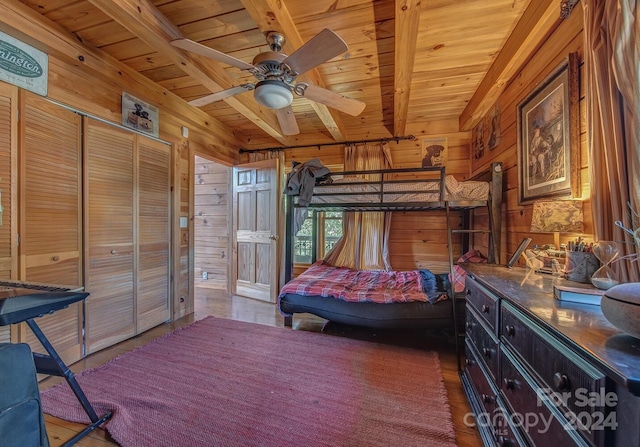 bedroom featuring beam ceiling, wooden walls, and ceiling fan