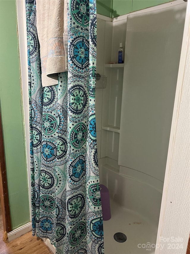 bathroom with curtained shower and hardwood / wood-style flooring