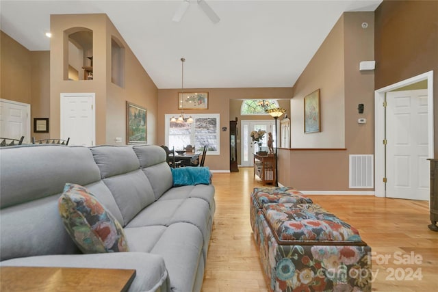 living room featuring ceiling fan with notable chandelier, light wood-type flooring, and high vaulted ceiling