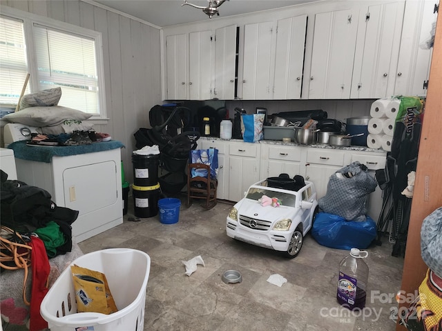 kitchen with crown molding, wood walls, washer / clothes dryer, and white cabinets