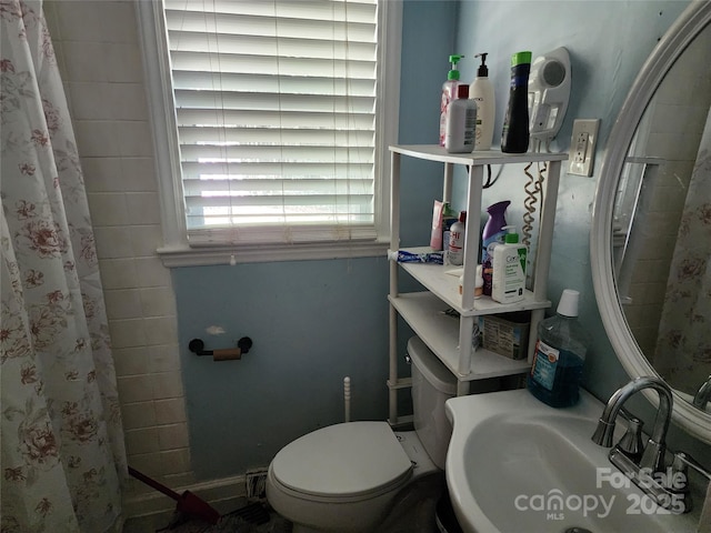 bathroom with walk in shower, sink, and toilet