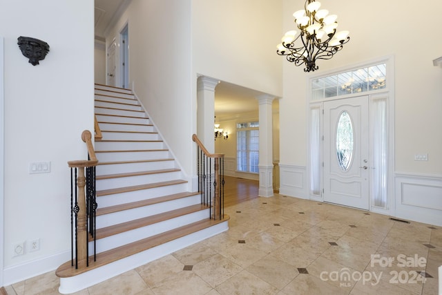 foyer entrance with ornate columns and an inviting chandelier