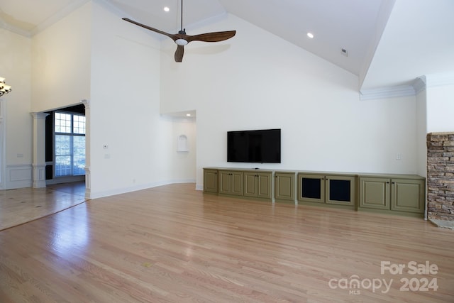 unfurnished living room with ornamental molding, light hardwood / wood-style flooring, high vaulted ceiling, and ceiling fan