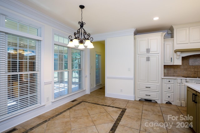 kitchen featuring decorative backsplash, white cabinetry, a chandelier, pendant lighting, and crown molding