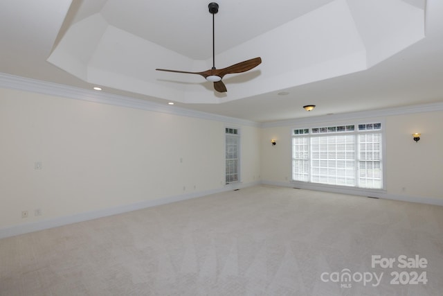 carpeted empty room with crown molding, a tray ceiling, and ceiling fan