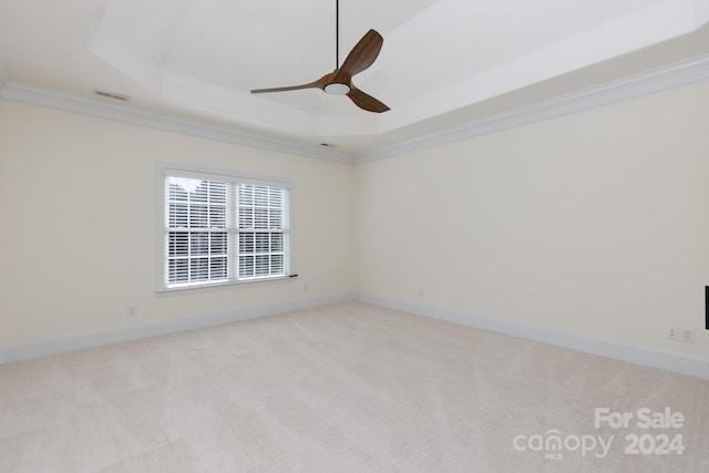 empty room featuring crown molding, a raised ceiling, light colored carpet, and ceiling fan