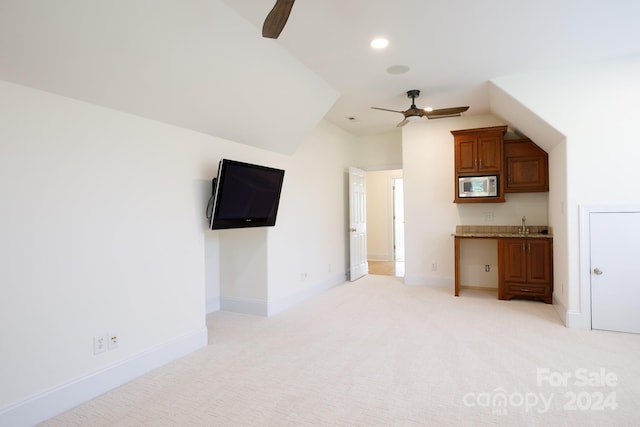 unfurnished living room featuring ceiling fan, lofted ceiling, and light colored carpet