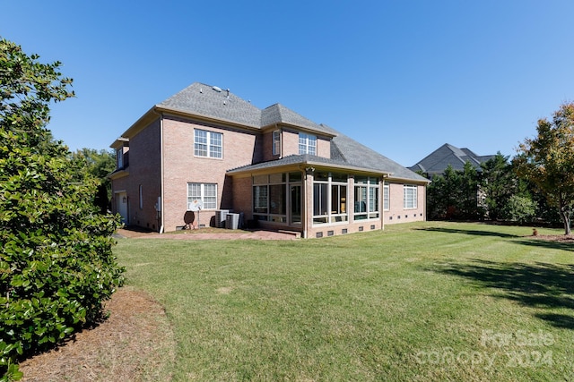 back of property with central AC, a yard, and a sunroom