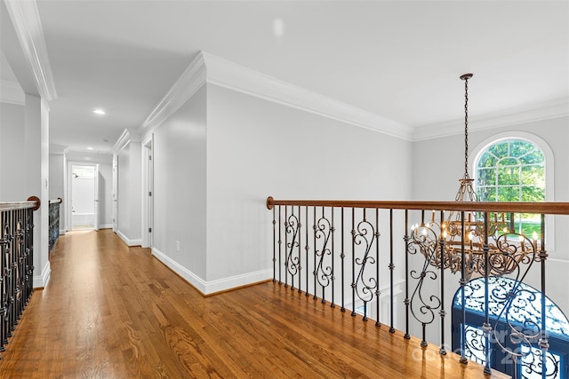 hall with ornamental molding, hardwood / wood-style floors, and an inviting chandelier