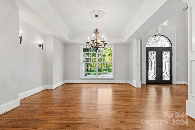 foyer with an inviting chandelier, french doors, hardwood / wood-style flooring, and a raised ceiling