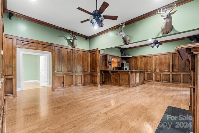 kitchen featuring stainless steel refrigerator, ornamental molding, light wood-type flooring, and a kitchen breakfast bar