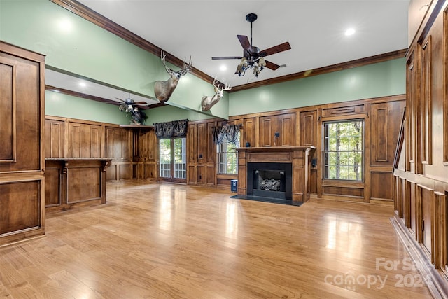 unfurnished living room featuring ornamental molding, wooden walls, light wood-type flooring, and ceiling fan