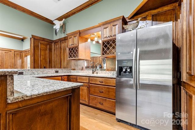 kitchen with stainless steel fridge with ice dispenser, light wood-type flooring, sink, crown molding, and light stone counters