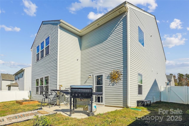 rear view of house featuring a gate, a patio area, fence, and a vegetable garden