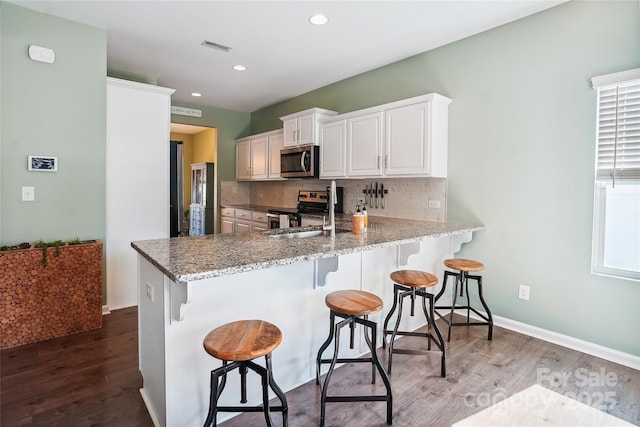 kitchen with a breakfast bar, stainless steel appliances, decorative backsplash, and wood finished floors