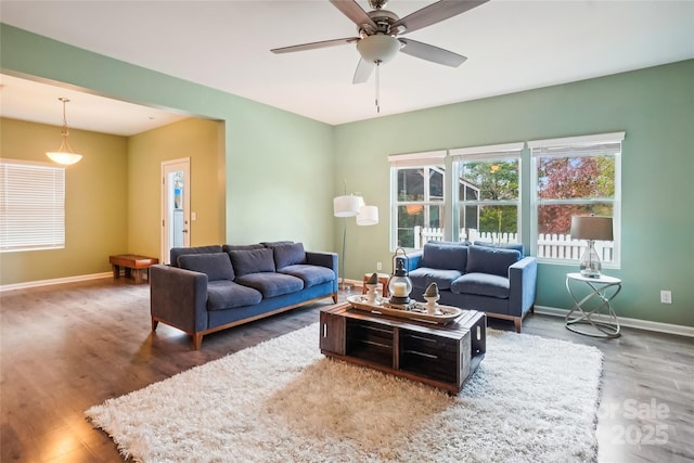 living room with a ceiling fan, baseboards, and wood finished floors