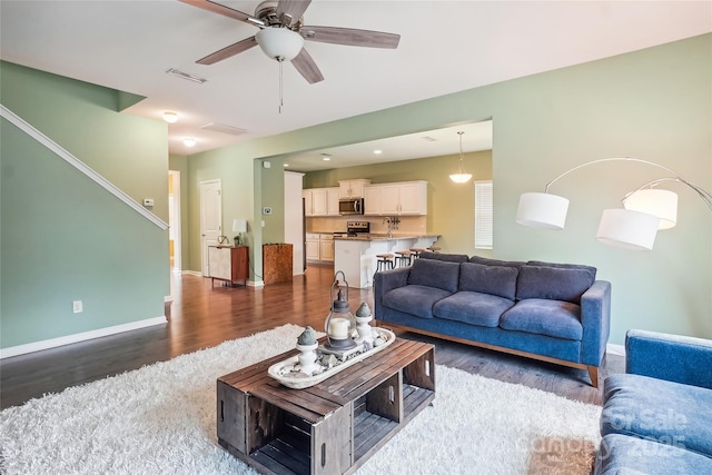 living area with visible vents, dark wood finished floors, baseboards, and ceiling fan