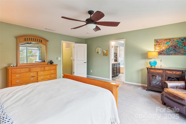 bedroom featuring baseboards, ceiling fan, ensuite bathroom, and light colored carpet