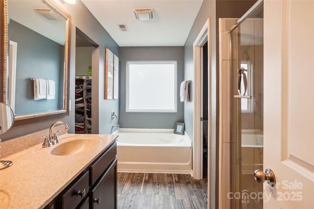 full bathroom featuring a garden tub, wood finished floors, visible vents, vanity, and a shower stall