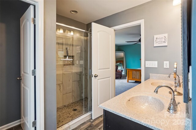 bathroom with ceiling fan, double vanity, a sink, and a shower stall