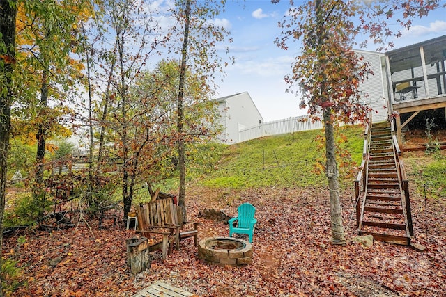 view of yard with a fire pit, fence, and stairway