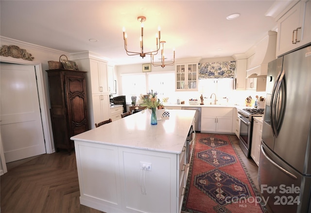 kitchen featuring a center island, white cabinets, crown molding, pendant lighting, and appliances with stainless steel finishes