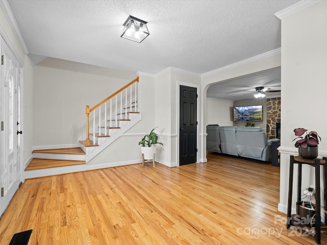 foyer entrance with crown molding, wood-type flooring, a textured ceiling, and ceiling fan