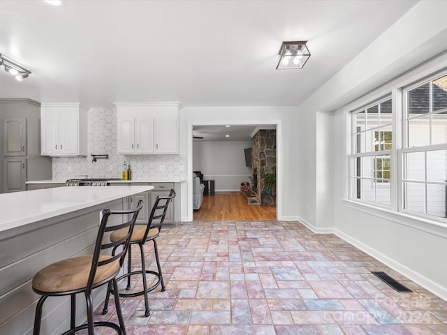 kitchen featuring a breakfast bar area, decorative backsplash, and white cabinetry