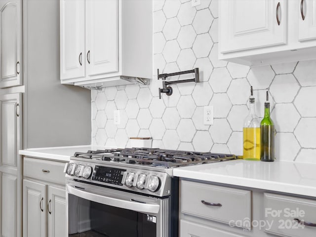 kitchen with decorative backsplash, white cabinetry, and gas stove