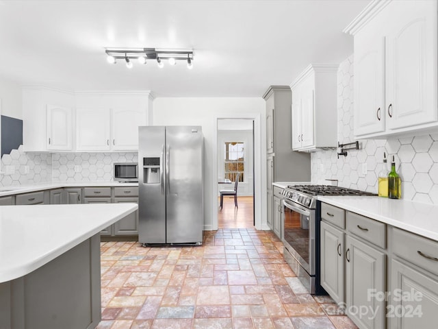 kitchen featuring stainless steel appliances, track lighting, backsplash, and gray cabinetry