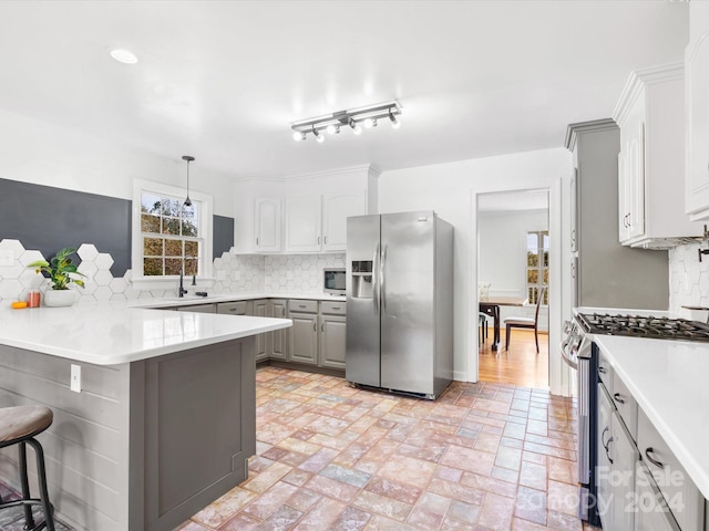 kitchen with backsplash, hanging light fixtures, stainless steel appliances, and a healthy amount of sunlight