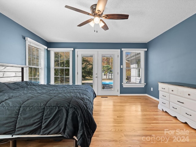 bedroom with light hardwood / wood-style flooring, a textured ceiling, access to outside, and ceiling fan