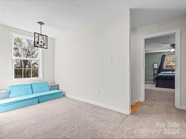 unfurnished room featuring light carpet, a textured ceiling, and ceiling fan with notable chandelier