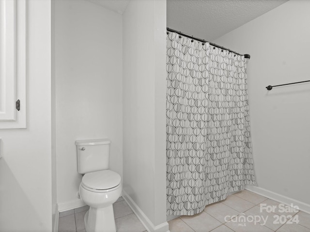 bathroom featuring walk in shower, toilet, tile patterned floors, and a textured ceiling