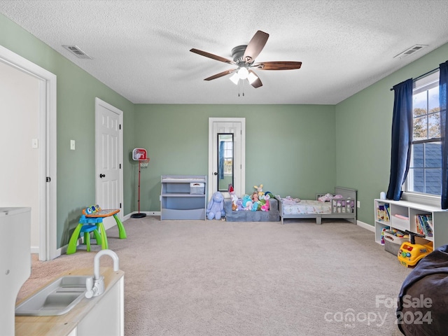 bedroom with a textured ceiling, carpet flooring, and ceiling fan