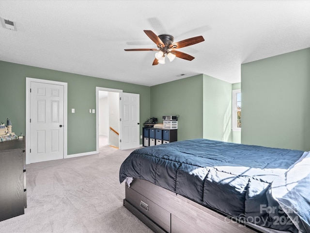 carpeted bedroom featuring ceiling fan and a textured ceiling