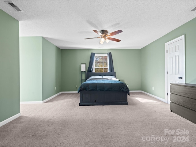 carpeted bedroom featuring a textured ceiling and ceiling fan