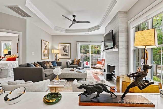 living room with ceiling fan, a high end fireplace, a healthy amount of sunlight, and crown molding