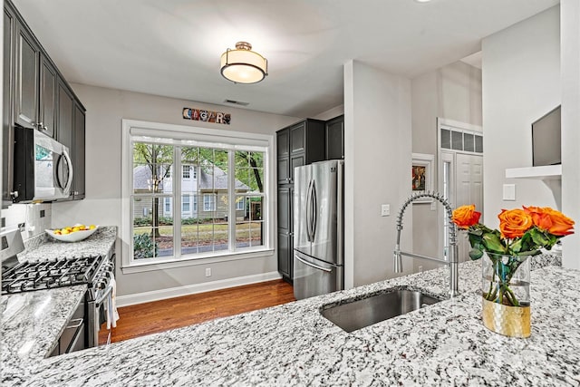 kitchen featuring stainless steel appliances, sink, dark hardwood / wood-style floors, and light stone countertops