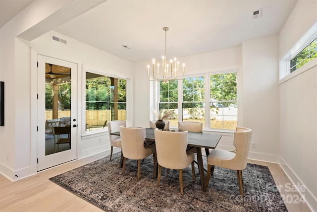 dining space with light wood-type flooring, an inviting chandelier, and plenty of natural light