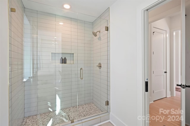 bathroom featuring wood-type flooring and a shower with shower door