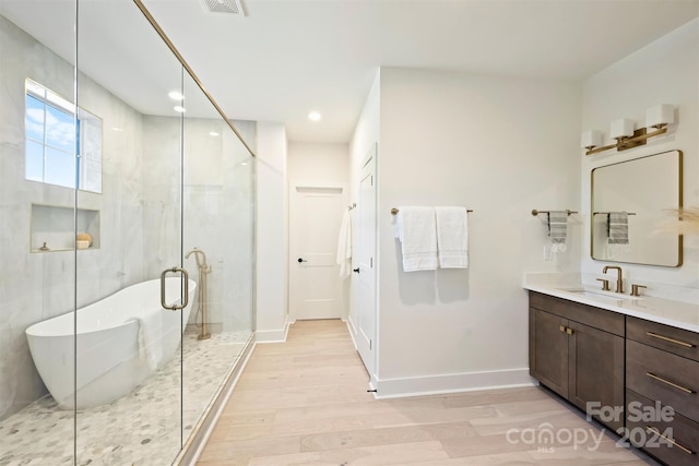 bathroom with shower with separate bathtub, vanity, and hardwood / wood-style floors