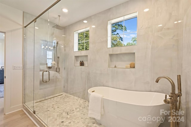 bathroom with tile walls, hardwood / wood-style flooring, and separate shower and tub