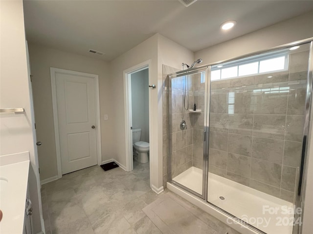 bathroom with vanity, toilet, and a shower with door