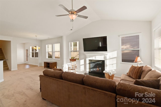 living room with lofted ceiling, light colored carpet, and ceiling fan with notable chandelier